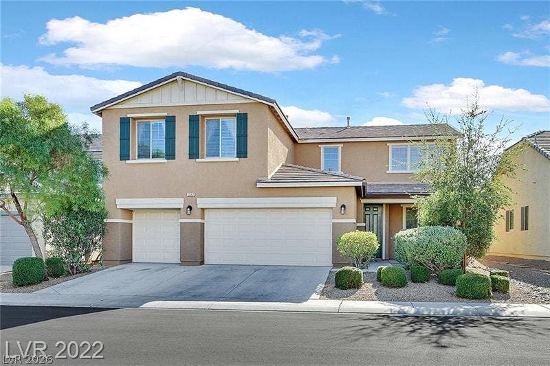 A classic two-story exterior features a tiled roof, multi-car garage, and neat desert landscaping.