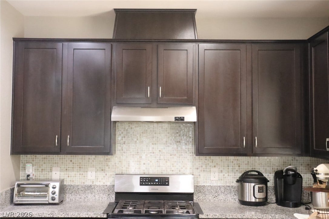 Rich dark wood cabinetry accents the kitchen above sleek granite countertops.