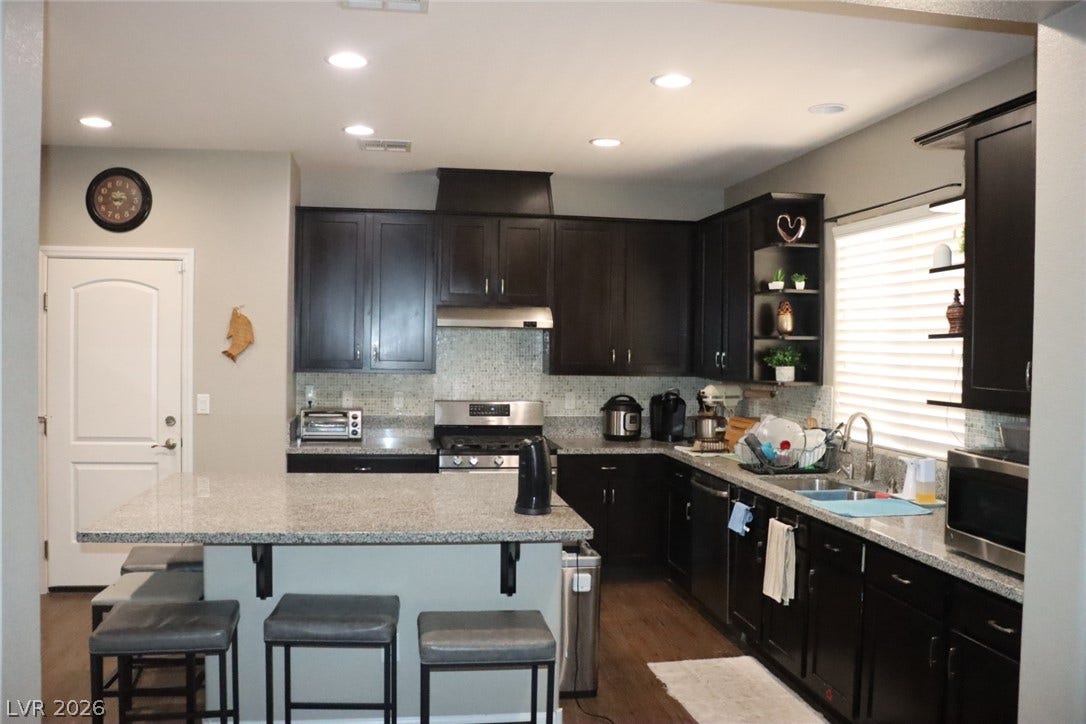 Rich dark cabinetry and stone countertops anchors this well-equipped kitchen space.
