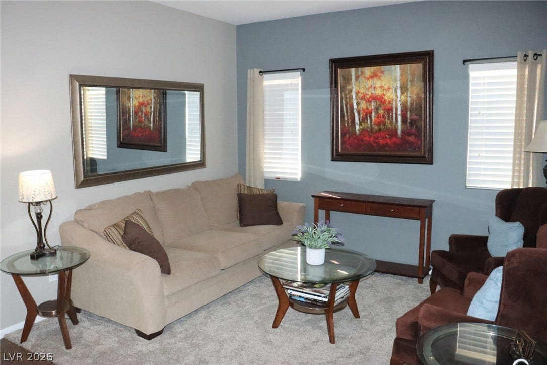 Natural light streams through twin windows, illuminating the comfortable carpeted living space.