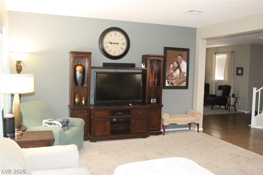 An open doorway connects the carpeted living space to an adjacent room with hardwood flooring.