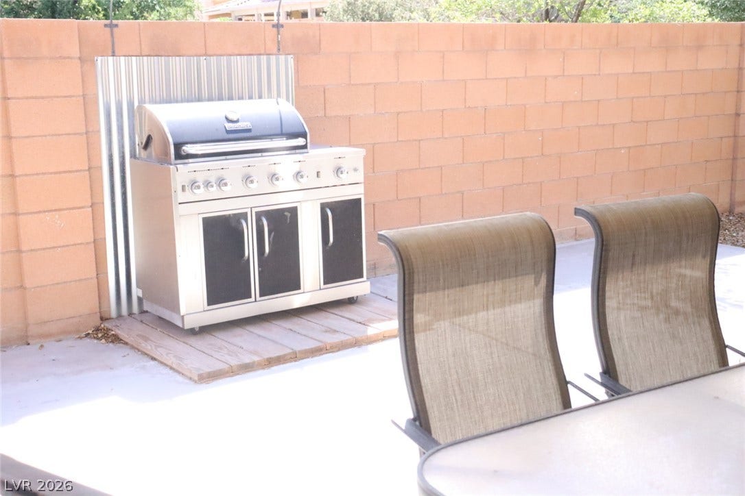 An inviting outdoor patio space features a built-in grill area against a privacy block wall.
