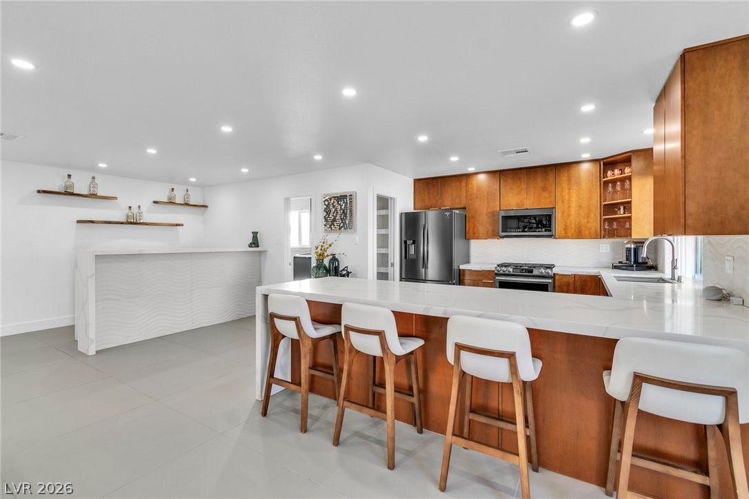 4170 Sheppard Drive, Las Vegas, NV 89121 Gleaming stone countertops and warm wood cabinetry anchor a modern, open kitchen design.