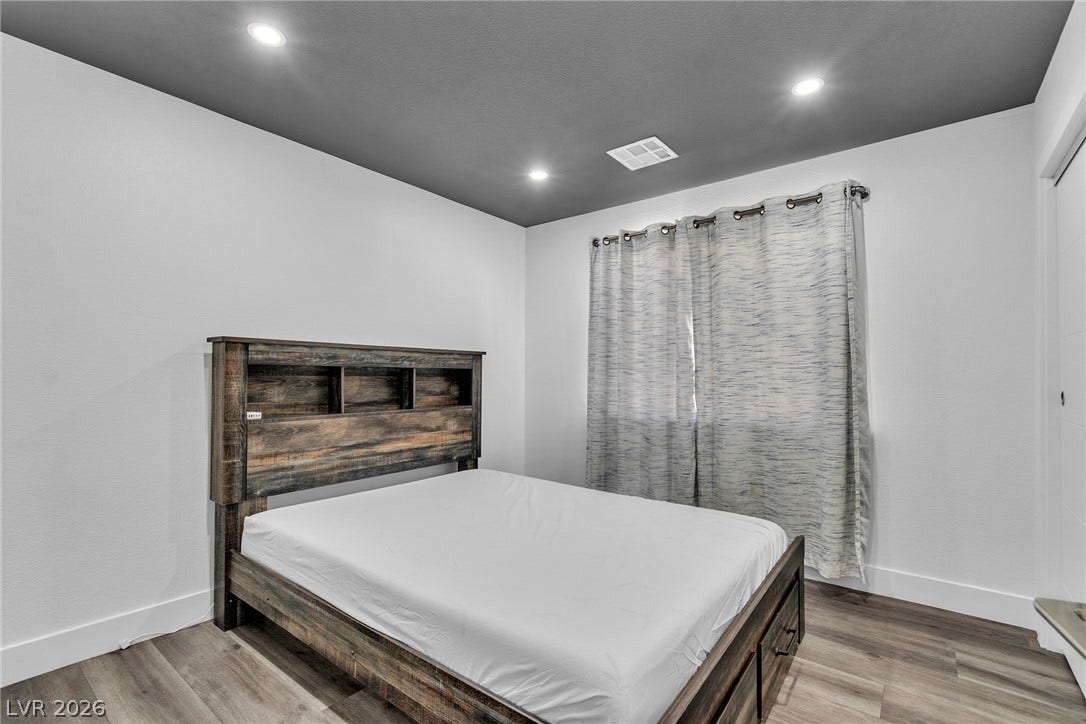 4170 Sheppard Drive, Las Vegas, NV 89121 Recessed lighting illuminates wood-look flooring and a contrasting dark ceiling in this cozy bedroom.