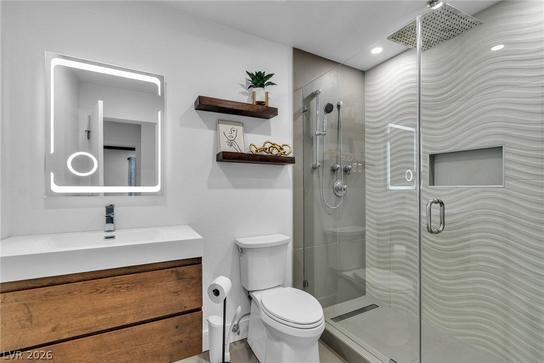 4170 Sheppard Drive, Las Vegas, NV 89121 Modern finishes define this bathroom highlighting a glass-enclosed shower with textured tile work.