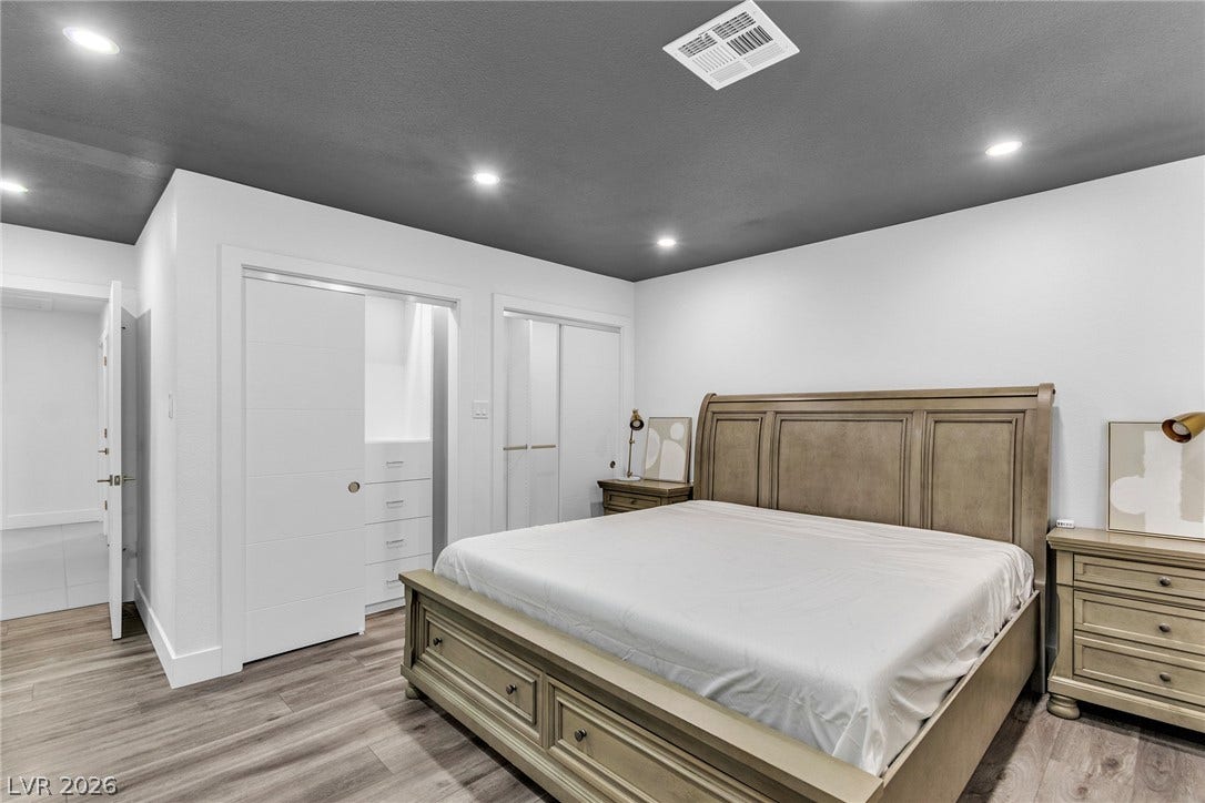 4170 Sheppard Drive, Las Vegas, NV 89121 Recessed lighting glows over wood-look flooring and clean white walls in this modern bedroom.