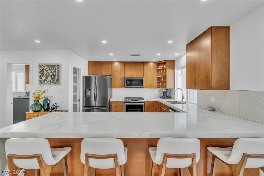 4170 Sheppard Drive, Las Vegas, NV 89121 An expansive stone-topped breakfast bar opens into this modern kitchen featuring warm wood cabinetry.