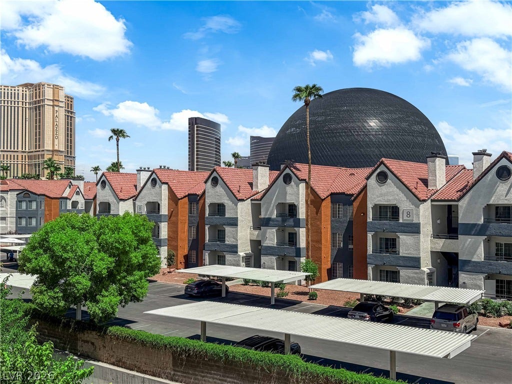 220 E Flamingo Road, #117, Las Vegas, NV 89169 Multi-level residential structures show tile roofing and covered parking against a city backdrop.