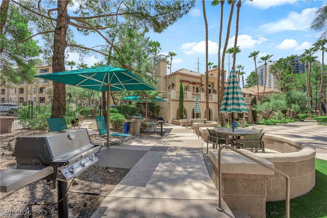 220 E Flamingo Road, #117, Las Vegas, NV 89169 Paved concrete pathways wind through a landscaped courtyard featuring stone retaining walls and palm trees.