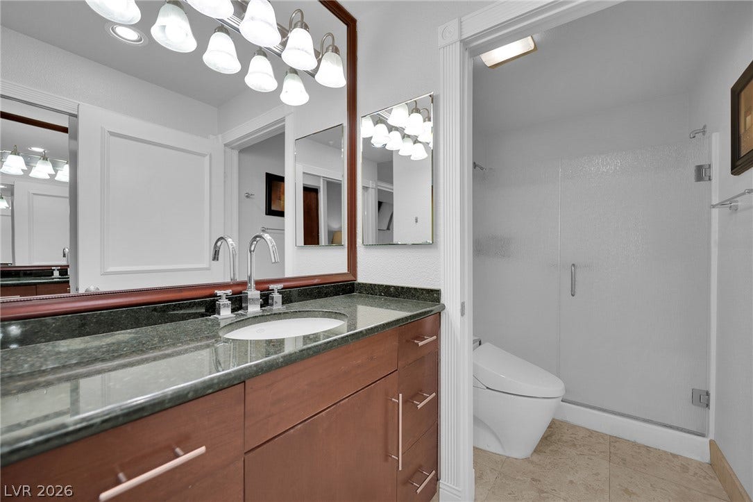 220 E Flamingo Road, #117, Las Vegas, NV 89169 Gleaming stone countertops and warm wood cabinetry anchor this elegant bathroom space.