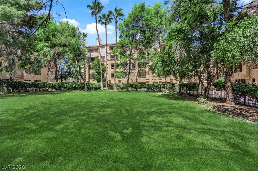 220 E Flamingo Road, #117, Las Vegas, NV 89169 A manicured green lawn is surrounded by mature trees and towering palms.