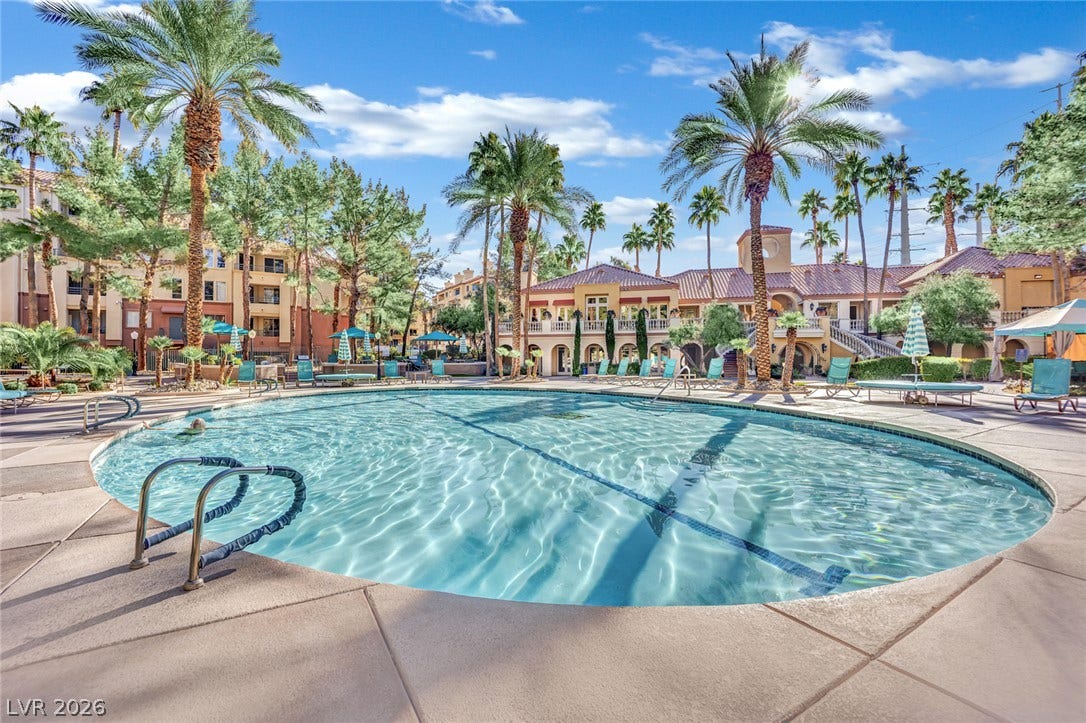 220 E Flamingo Road, #117, Las Vegas, NV 89169 Palm trees frame a sparkling community pool set against a clear blue sky.