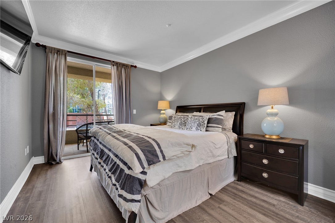 220 E Flamingo Road, #117, Las Vegas, NV 89169 Crown molding and wide-plank flooring frame this bedroom opening directly onto a private balcony.