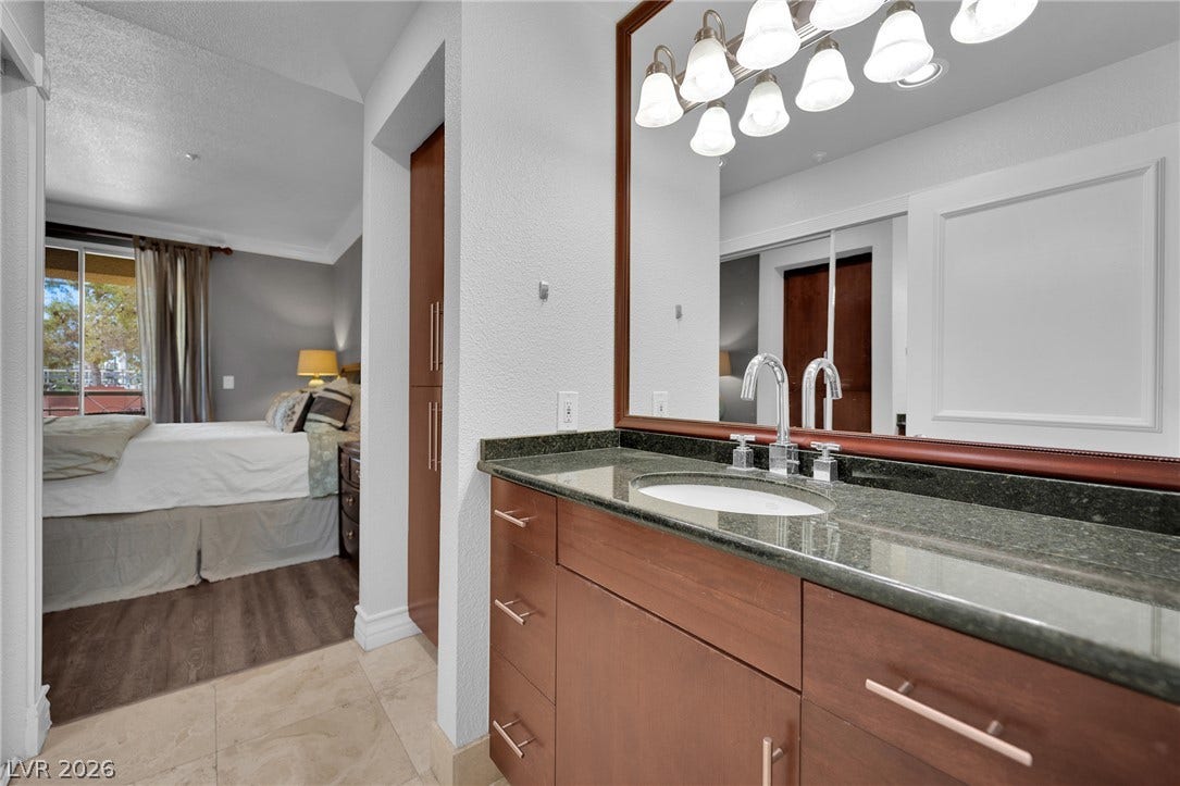 220 E Flamingo Road, #117, Las Vegas, NV 89169 A stone-topped vanity stands adjacent to the bedroom entryway, flanked by tile flooring.