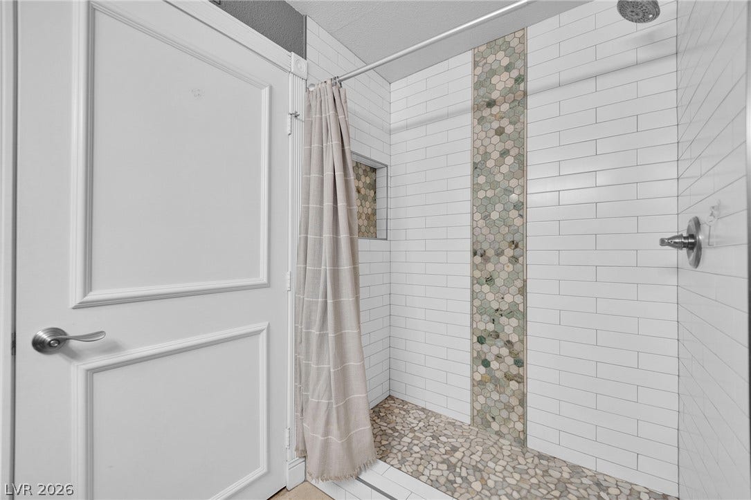 220 E Flamingo Road, #117, Las Vegas, NV 89169 Crisp subway tile surrounds a walk-in shower with textured pebble flooring and custom niche details.