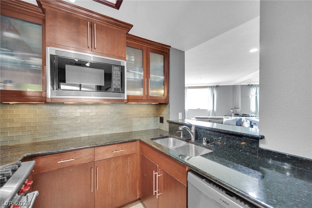 220 E Flamingo Road, #117, Las Vegas, NV 89169 Gleaming stone countertops and a tiled backsplash elevate this open-concept kitchen space.