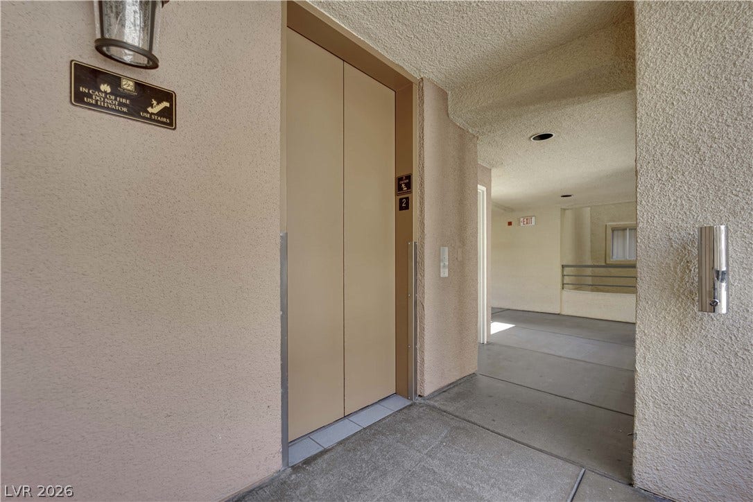 220 E Flamingo Road, #117, Las Vegas, NV 89169 Stucco walls and concrete flooring frame this functional residential elevator lobby.