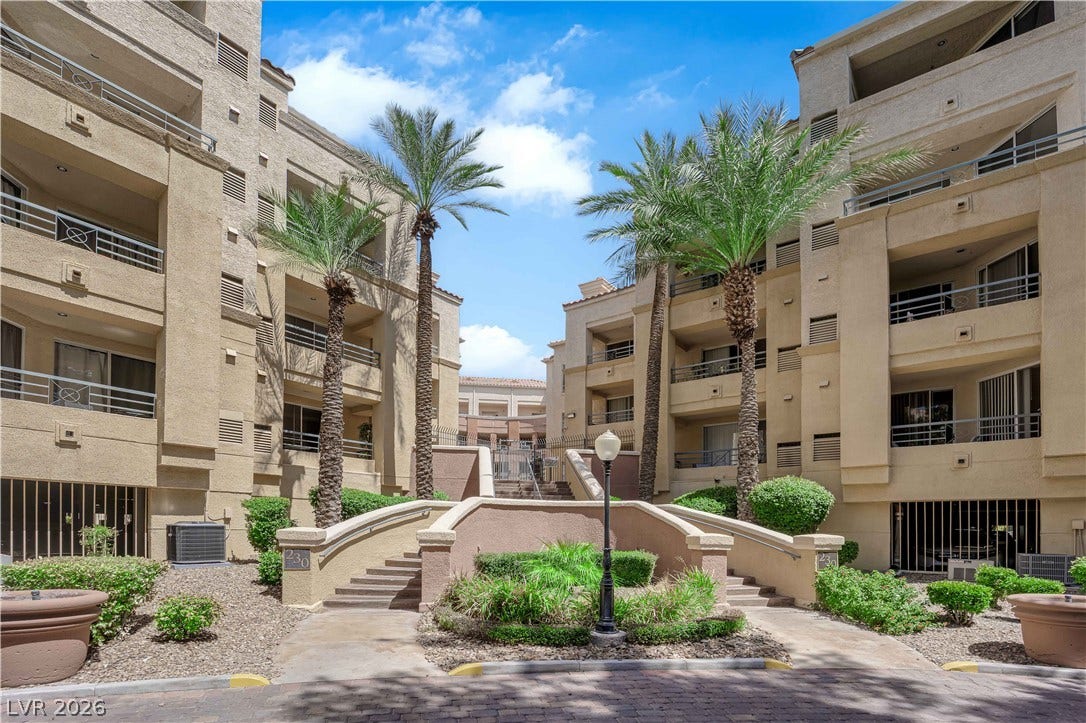 220 E Flamingo Road, #117, Las Vegas, NV 89169 Stately stucco facades surround a central landscaped entry path flanked by mature palm trees.