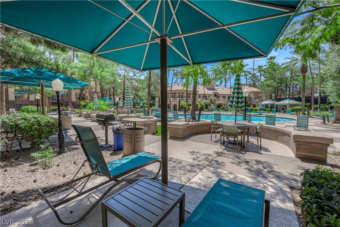 220 E Flamingo Road, #117, Las Vegas, NV 89169 Lush tropical landscaping surrounds a shared poolside courtyard featuring paved sunbathing decks and dining areas.
