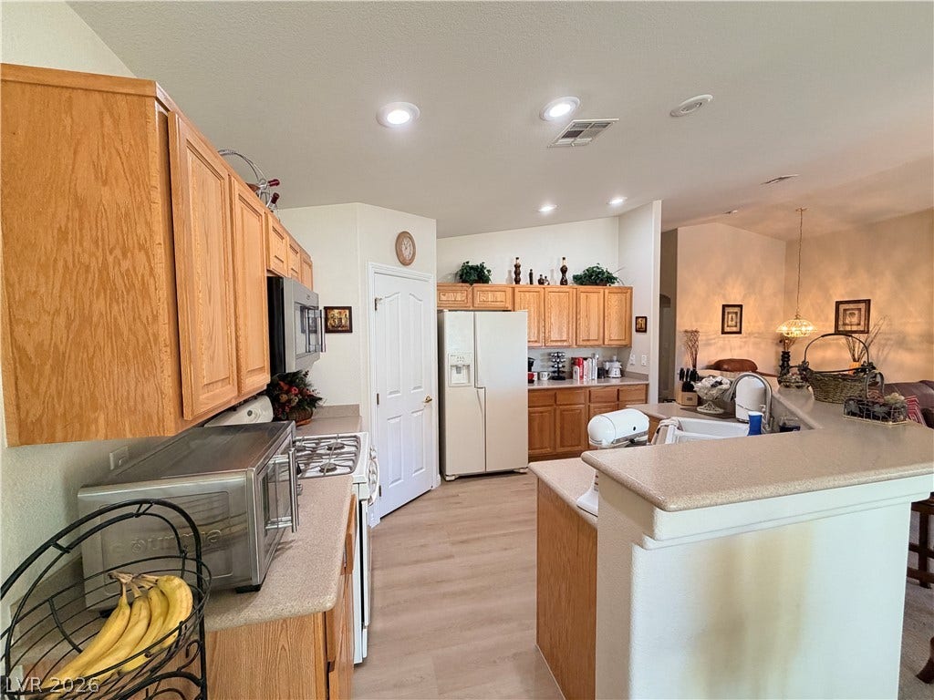 3917 Robin Knot Court, North Las Vegas, NV 89084 Oak cabinetry and a raised breakfast bar anchor this open-concept kitchen.