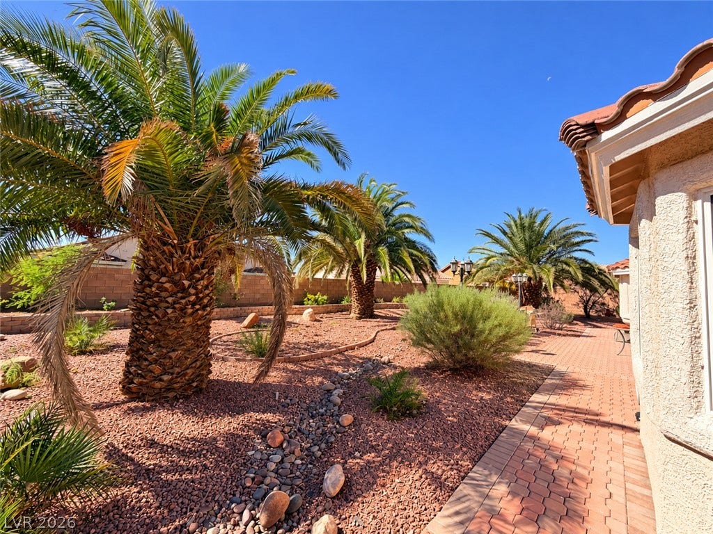 3917 Robin Knot Court, North Las Vegas, NV 89084 Lush palm trees and desert landscaping border a paved brick pathway along the home.