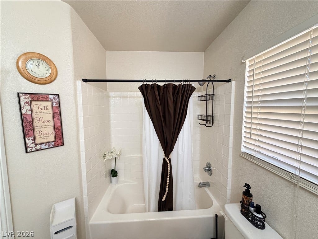 3917 Robin Knot Court, North Las Vegas, NV 89084 Crisp white wall tile surrounds the tub in this cozy, well-lit bathroom space.