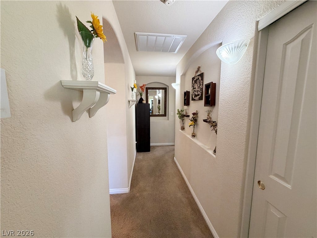 3917 Robin Knot Court, North Las Vegas, NV 89084 An inviting hallway showcases neutral textured walls, built-in display niches, and soft carpet flooring.