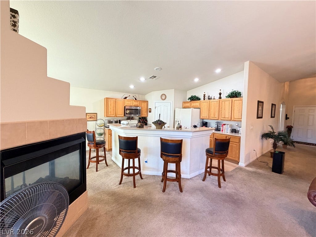 3917 Robin Knot Court, North Las Vegas, NV 89084 An open floor plan connects the kitchen and living space featuring a cozy tiled fireplace.
