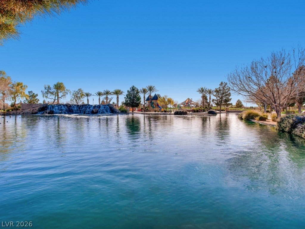 3917 Robin Knot Court, North Las Vegas, NV 89084 Scenic community lake views feature mature trees and a distant rock waterfall under blue skies.