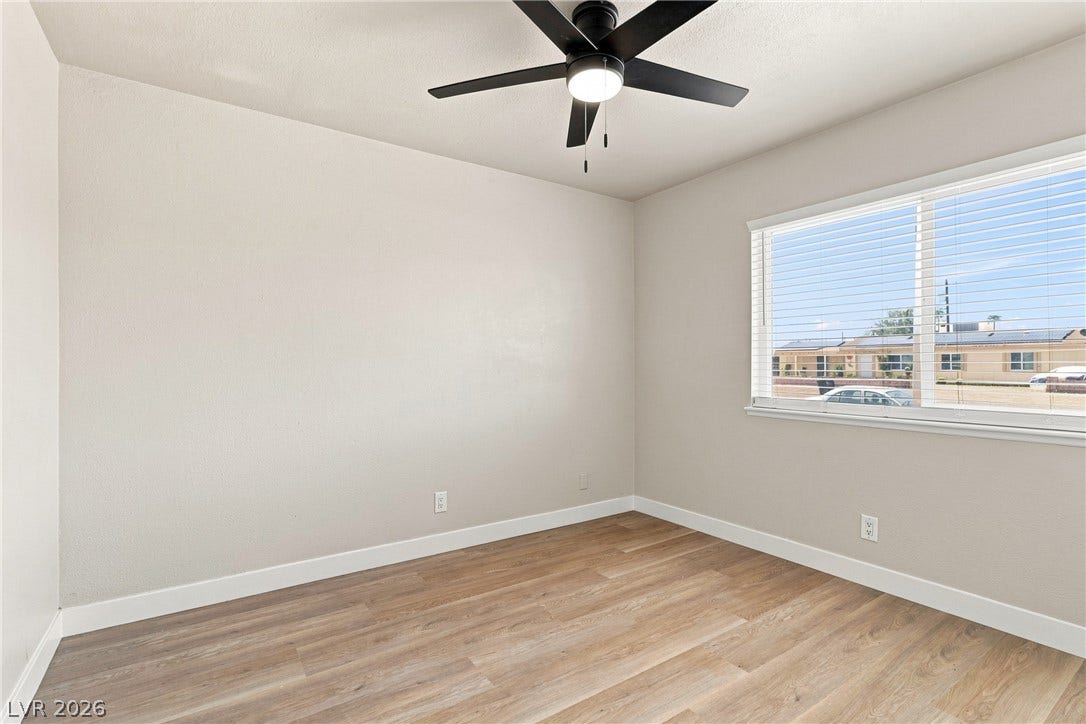 Smooth wood-style flooring and a large window define this versatile bedroom space.