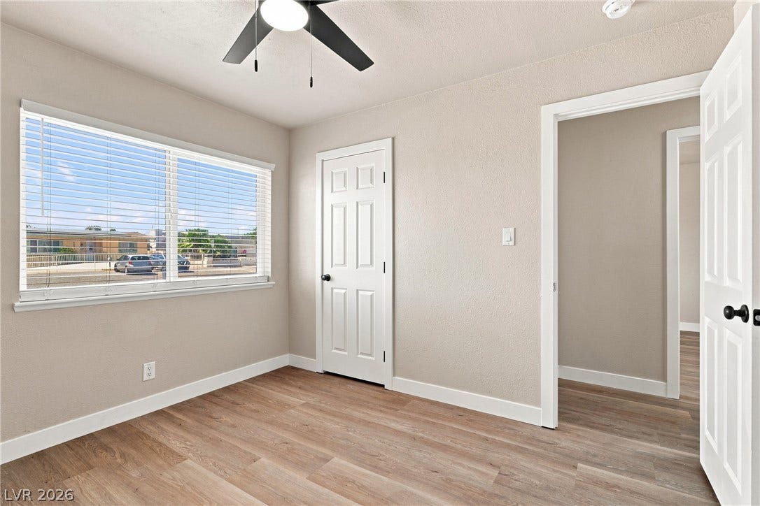 Gleaming wood flooring complements the neutral walls and dual doorways in this bright bedroom.