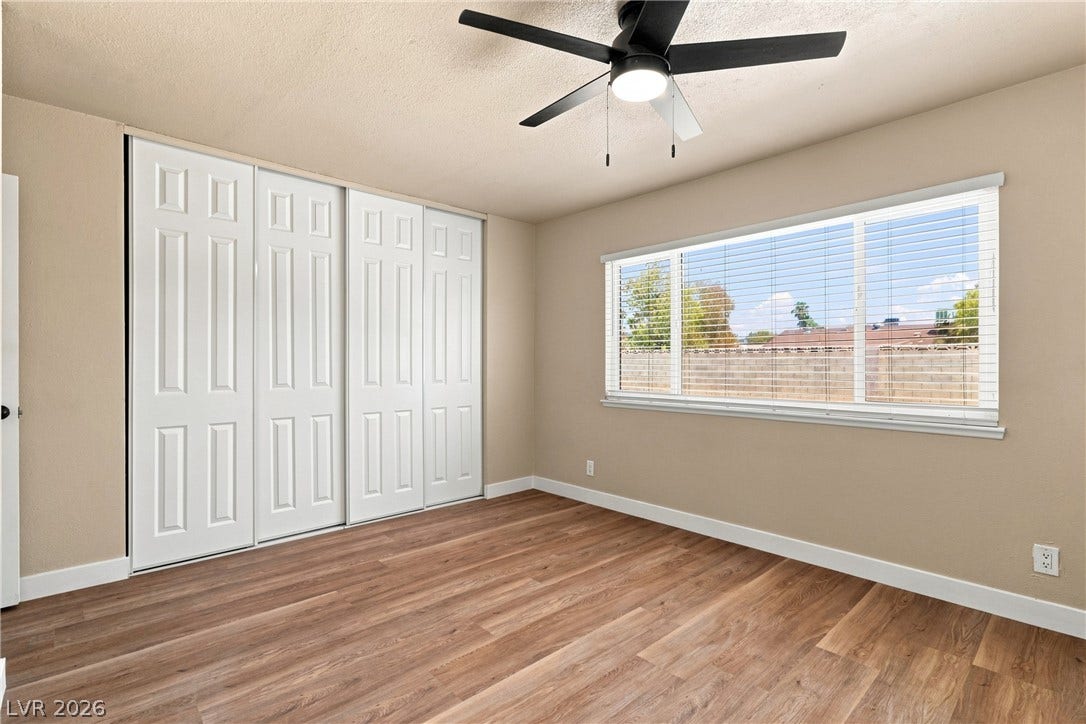 Rich wood-inspired flooring and ample closet space define this comfortable, light-filled bedroom.