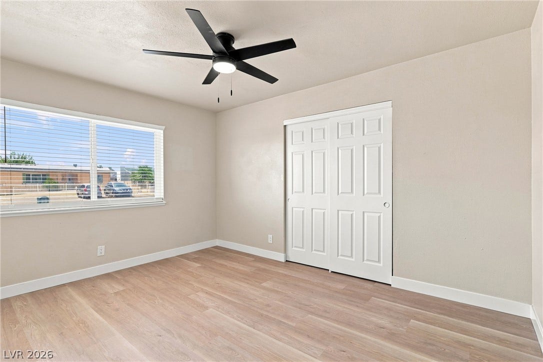 Smooth wood-look flooring and a wide window with integrated blinds define this versatile space.