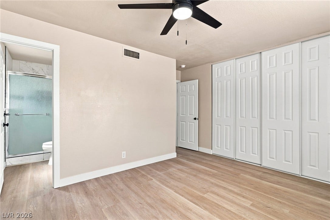 Smooth wood-style flooring runs through this bedroom featuring sliding closet doors and an attached bath.