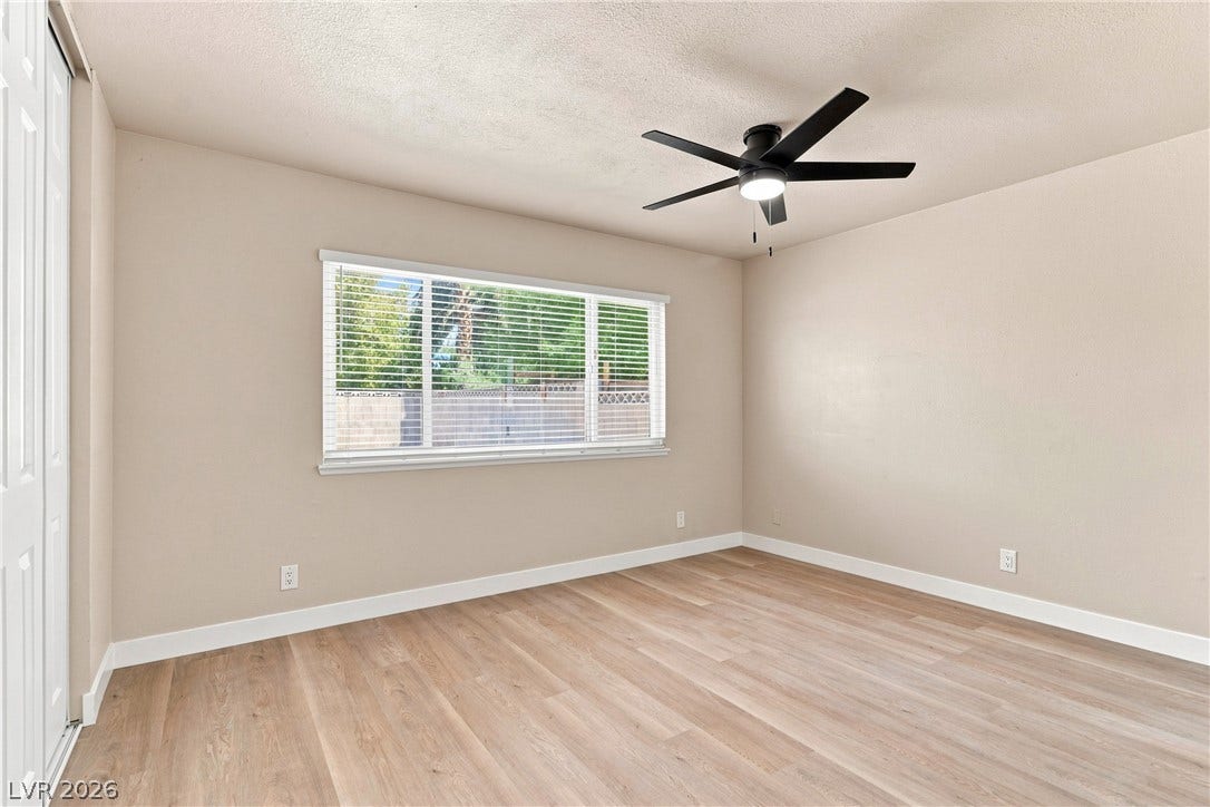 Smooth wood-style flooring and a wide window with integrated blinds enhance this versatile interior space.