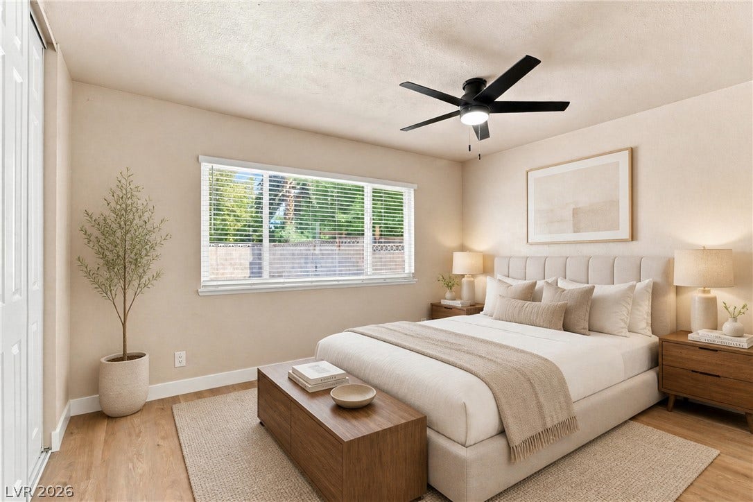 **Virtually Staged** Natural light streams through a wide window onto warm wood flooring in this bedroom.