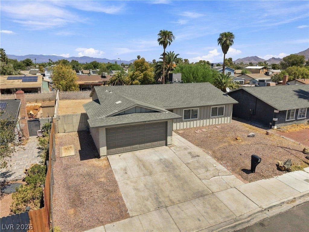 A spacious driveway leads to the attached garage under a classic shingle roof.