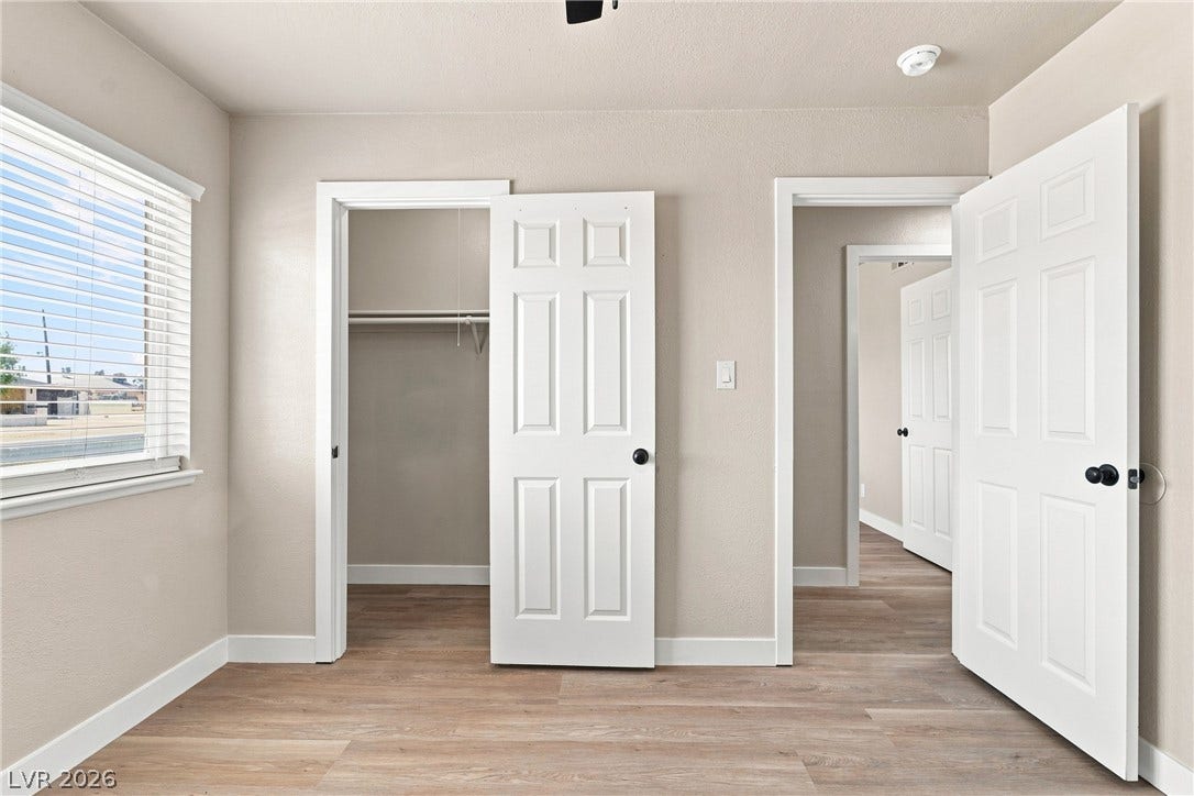 Smooth wood-look flooring and classic panel doors define this bright, versatile bedroom space.