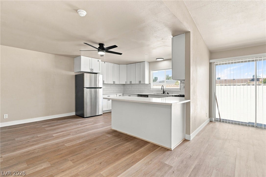 An open layout connects the dining space directly to a modern kitchen with sliding glass doors.