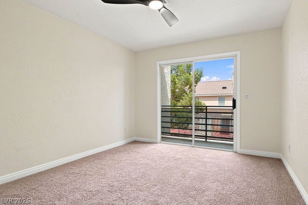 6250 W Flamingo Road, #62, Las Vegas, NV 89103 The spacious second bedroom features cozy carpeting, a modern ceiling fan, and sliding glass doors that fill the room with natural light and open to a private balcony.