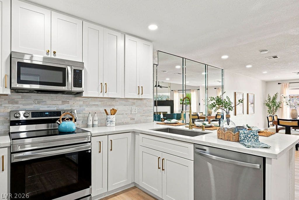 6250 W Flamingo Road, #62, Las Vegas, NV 89103 This updated modern white kitchen featuring gold hardware, stainless steel appliances, and a stylish tiled backsplash.