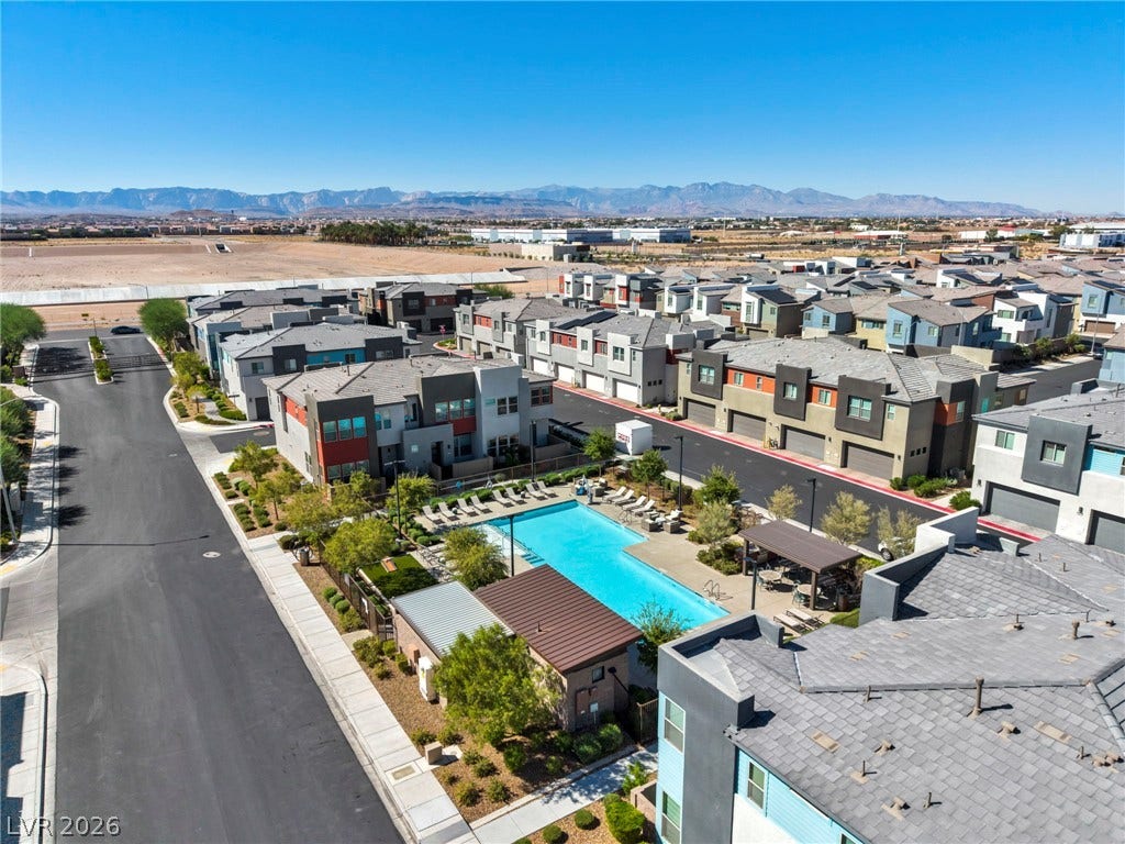 9826 Canyon Sage Street, Las Vegas, NV 89141 A sparkling community pool sits nestled among modern homes against a backdrop of distant mountains.