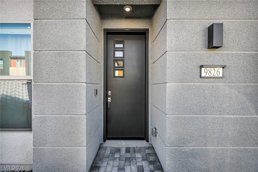 9826 Canyon Sage Street, Las Vegas, NV 89141 A modern recessed entrance features a contemporary dark door set against textured stucco walls.