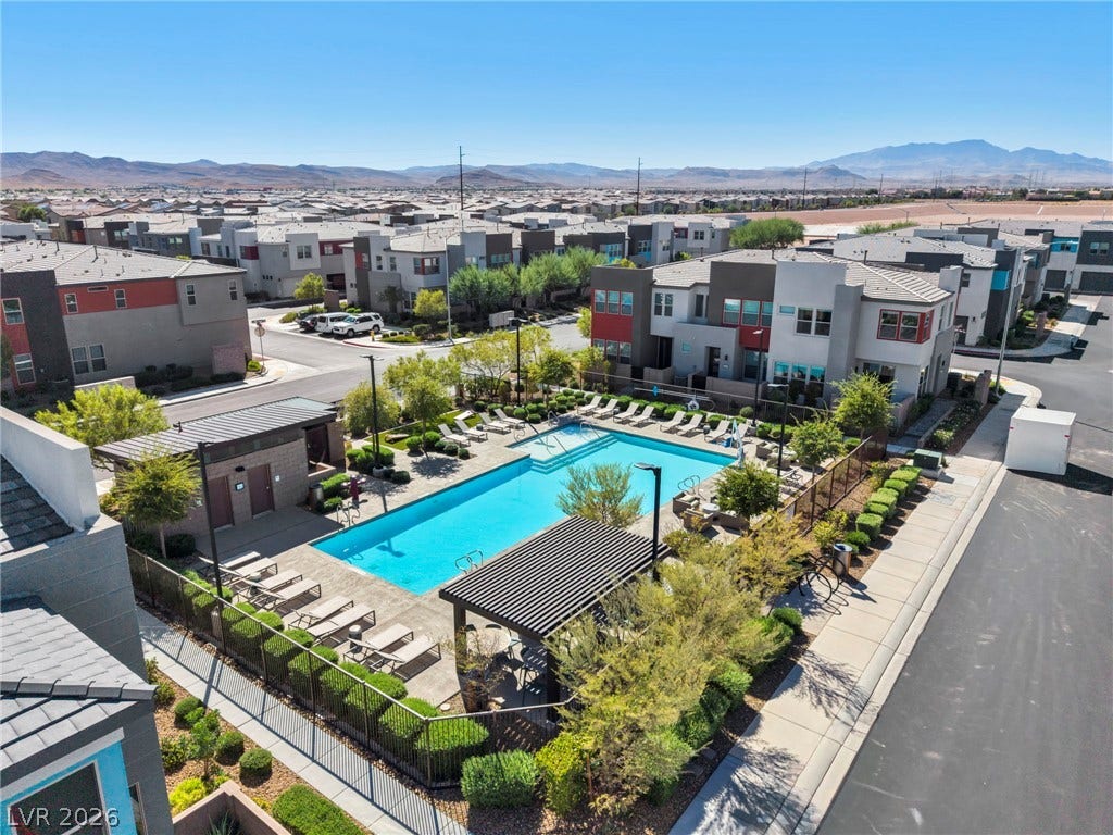 9826 Canyon Sage Street, Las Vegas, NV 89141 An inviting community swimming pool sits nested among modern residential buildings under clear desert skies.
