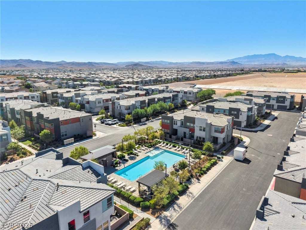 9826 Canyon Sage Street, Las Vegas, NV 89141 Aerial view captures a community swimming pool nested within modern residential architecture and desert mountain backdrops.