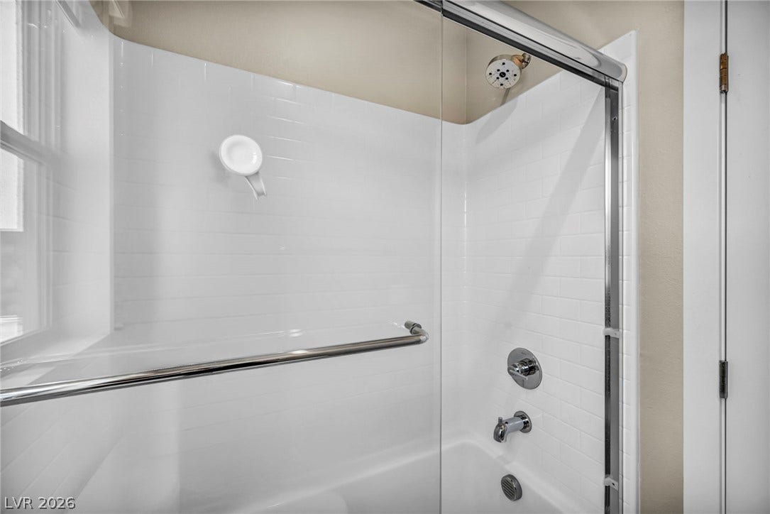 9826 Canyon Sage Street, Las Vegas, NV 89141 Clean subway tile walls surround a classic tub and shower combination with sliding glass doors.
