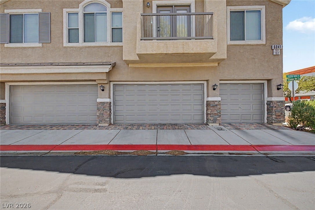 6041 Turning Spoke Trail, #102, Henderson, NV 89011 Stucco cladding and classic stone veneer detailing frame the attached garages below a private balcony.