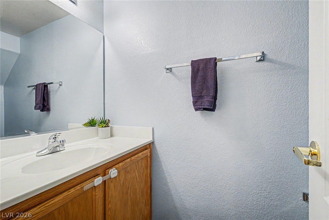 6041 Turning Spoke Trail, #102, Henderson, NV 89011 An integrated sink and natural wood vanity anchor this tidy half bath.