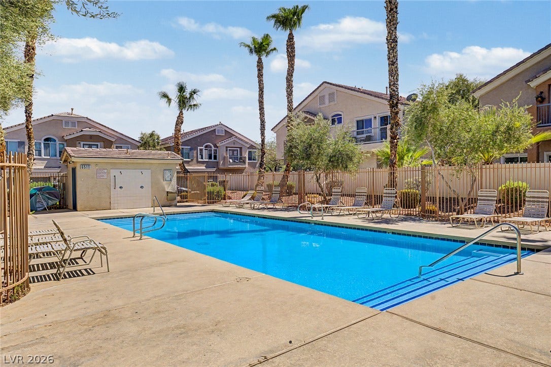6041 Turning Spoke Trail, #102, Henderson, NV 89011 Palm trees surround a clear swimming pool with concrete decking within a gated community.