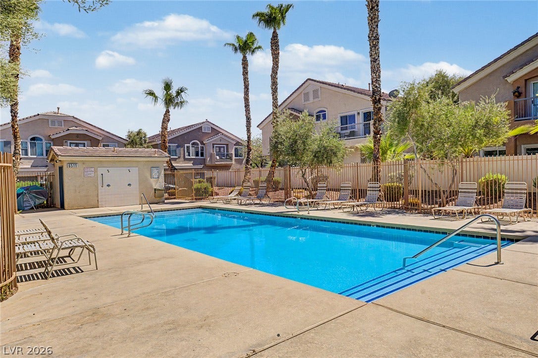 6041 Turning Spoke Trail, #102, Henderson, NV 89011 Palm trees surround a clear swimming pool enclosed by a security fence.